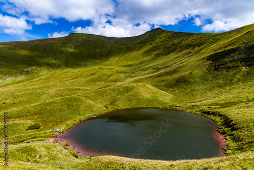 Beautiful small lake below towering, green mountains photo
