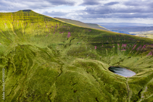 Aerial view of a small glacial lake beneath twin mountain peaks on a summers day photo