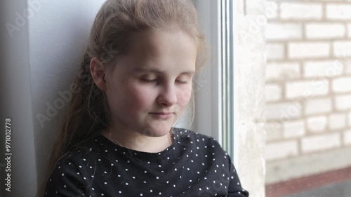 Teenage girl reading a book sitting on a windowsill and reasoning. Preparing homework. Reading a book and discussing it. Portrait of a smart, well-read girl sharing her thoughts