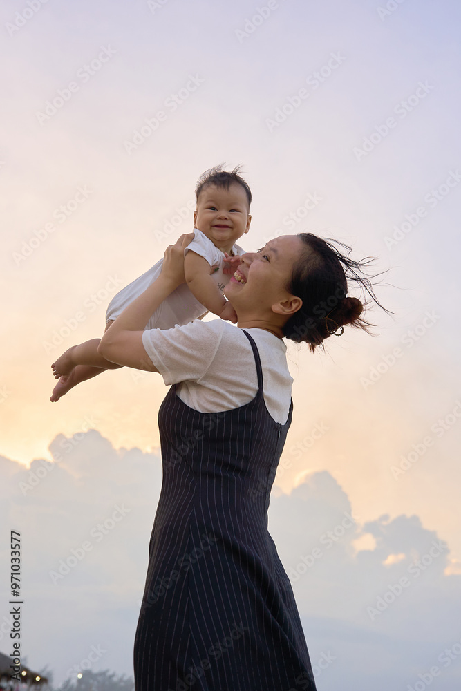 a woman holding a baby up in the air a woman holding a baby up in the air