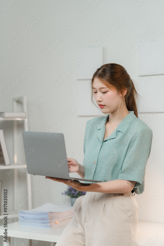 Focused Female Freelancer: Young Asian woman engrossed in her work on a laptop, highlighting the modern work-from-home lifestyle. Focused Female Freelancer: Young Asian woman engrossed in her work on a laptop, highlighting the modern work-from-home lifestyle.