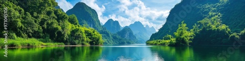 A beautiful mountain range with a river running through it. The water is calm and clear, reflecting the surrounding trees and mountains. The scene is peaceful and serene, with the lush greenery