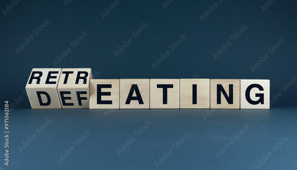 Obraz premium A conceptual image of wooden blocks spelling out the words Retreating and Defeating