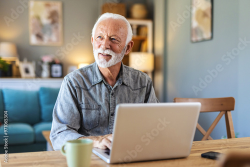 Senior man surfing on laptop at desk in apartment. Cropped shot of a senior man using his laptop while sitting at home.....