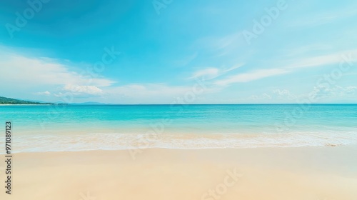 Relaxing tropical sandy beach with a soft-focus sea and clear blue sky, ideal for summer visuals.