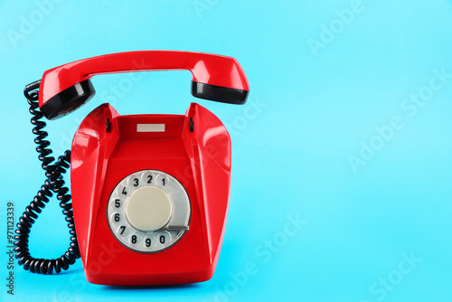 Red telephone with handset on light blue background, space for text