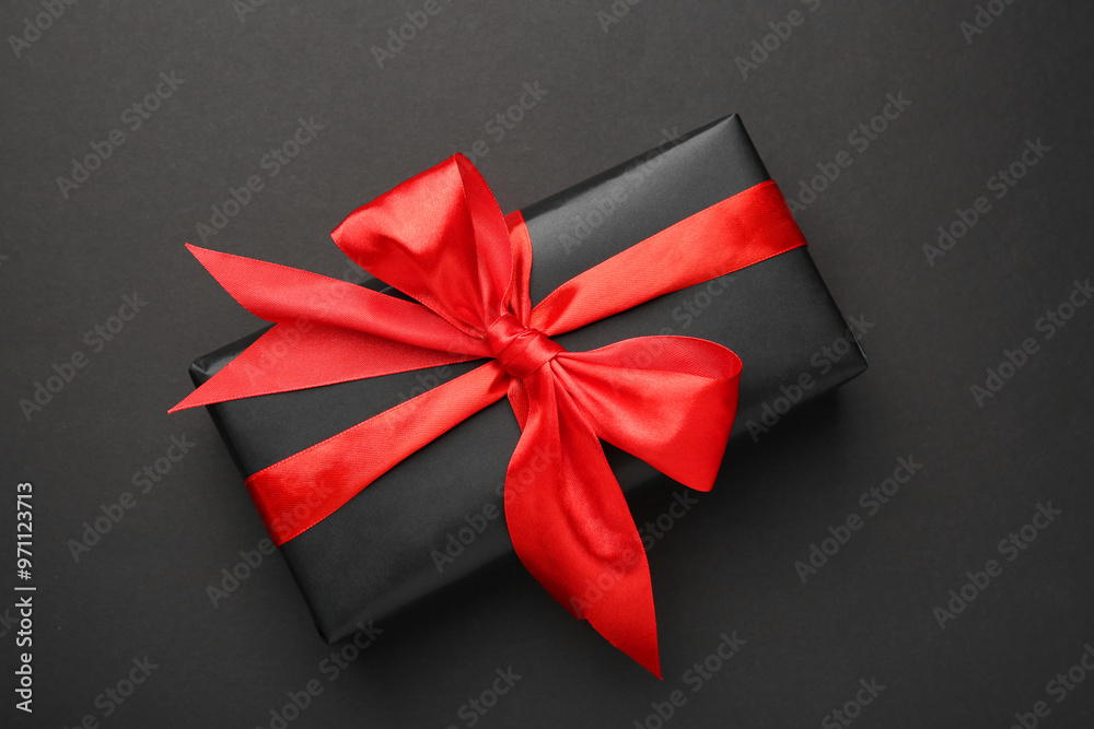 Gift box with red bow on black background, top view Gift box with red bow on black background, top view