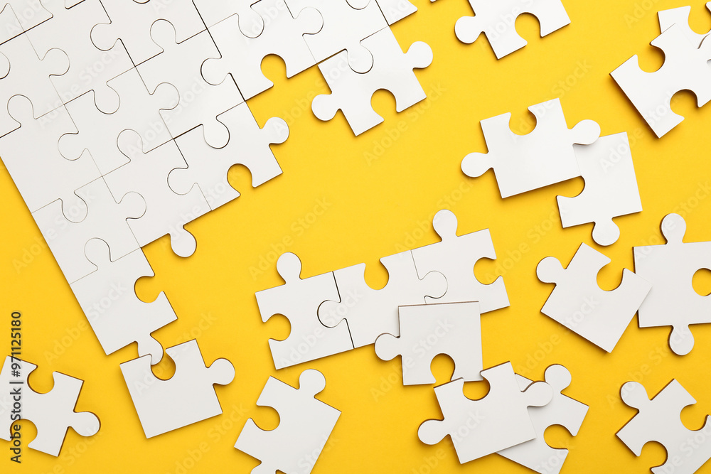 Naklejka premium White puzzle pieces on yellow background, top view