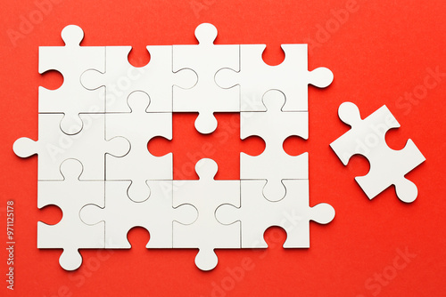 White puzzle pieces on red background, top view