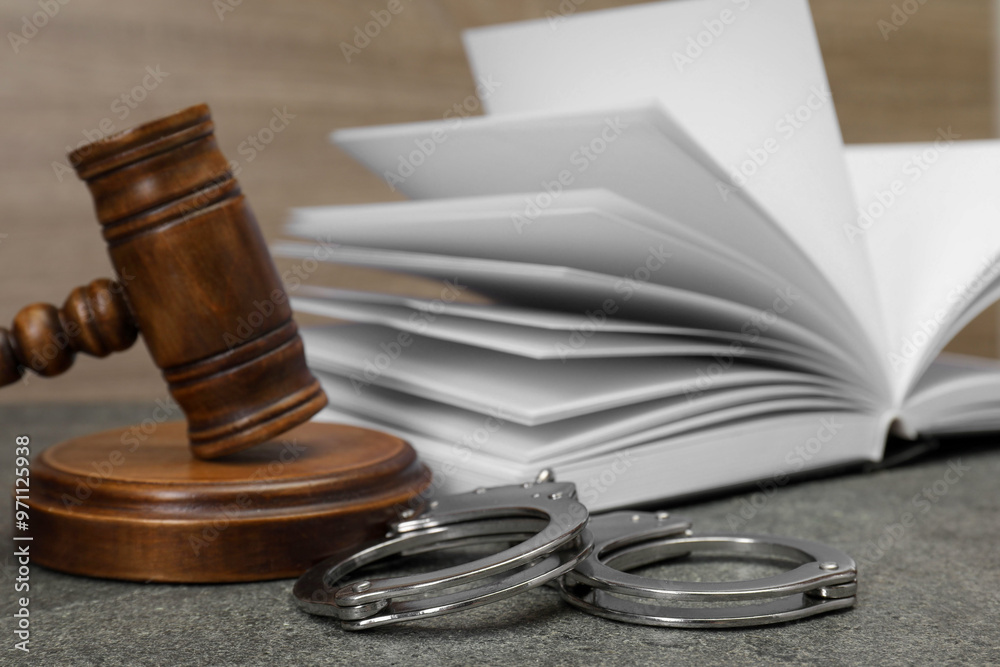 Book, judge's gavel and handcuffs on gray textured table, closeup Book, judge's gavel and handcuffs on gray textured table, closeup