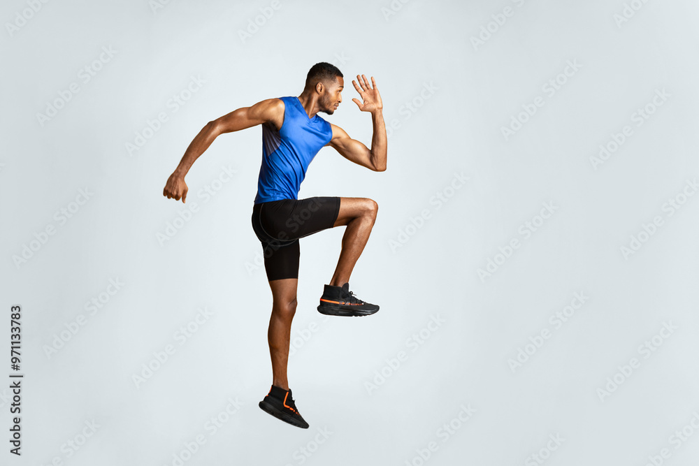 Obraz premium Doing Exercise. Full length portrait of muscular afro man with high knee, lifting leg and waving arm, copyspace