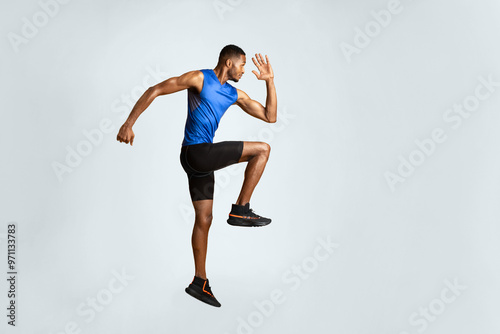 Doing Exercise. Full length portrait of muscular afro man with high knee, lifting leg and waving arm, copyspace