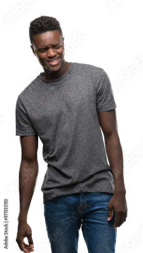 Young african american man wearing grey t-shirt looking away to side with smile on face, natural expression. Laughing confident.