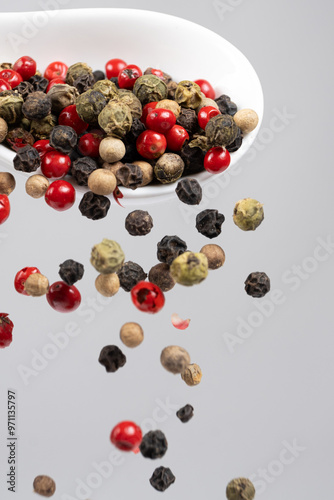 Different types of peppercorns pouring. Red, green, white and black pepper.