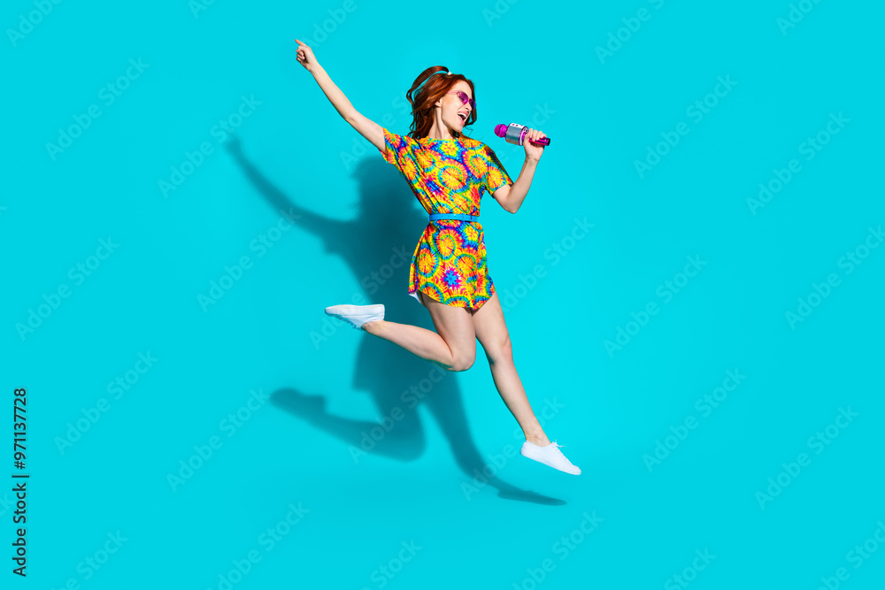 Full length photo of lovely young lady singing karaoke mic jump flying dressed stylish colorful garment isolated on cyan color background Full length photo of lovely young lady singing karaoke mic jump flying dressed stylish colorful garment isolated on cyan color background