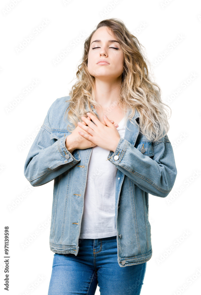 Beautiful young blonde woman wearing denim jacket over isolated background smiling with hands on chest with closed eyes and grateful gesture on face. Health concept. Beautiful young blonde woman wearing denim jacket over isolated background smiling with hands on chest with closed eyes and grateful gesture on face. Health concept.
