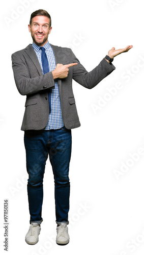 Handsome business man wearing suit and tie amazed and smiling to the camera while presenting with hand and pointing with finger.