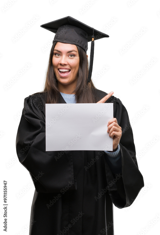 Young hispanic woman wearing graduated uniform holding diploma paper very happy pointing with hand and finger to the side Young hispanic woman wearing graduated uniform holding diploma paper very happy pointing with hand and finger to the side