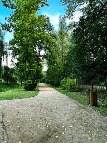 Winding path of a gravel pathway in a city park with many trees.
