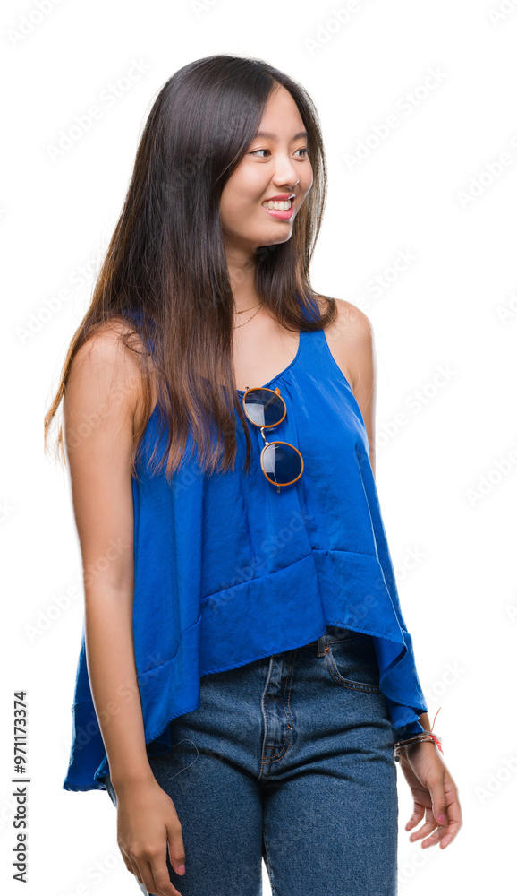 Fototapeta premium Young asian woman over isolated background looking away to side with smile on face, natural expression. Laughing confident.