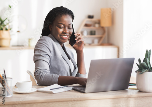 African American Businesswoman Talking On Cellphone And Using Laptop In Modern Office