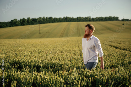 Having a walk. Man in white shirt is on the agricultural field