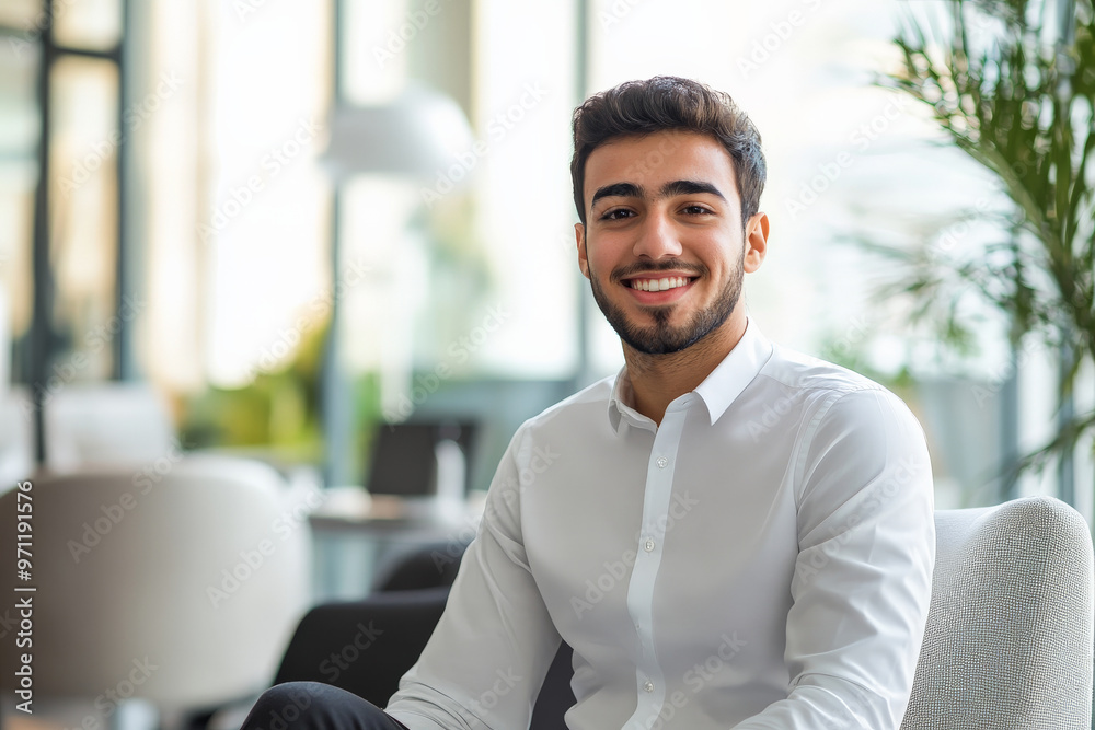 A young Arabian businessman, confidently smiling, looks at the camera from his sleek office space. The setting is modern, with high-end office equipment, clean lines, and a bright, inviting atmosphere
