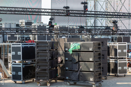 A large area is filled with stacked equipment cases and staging gear, being prepared for an upcoming event.