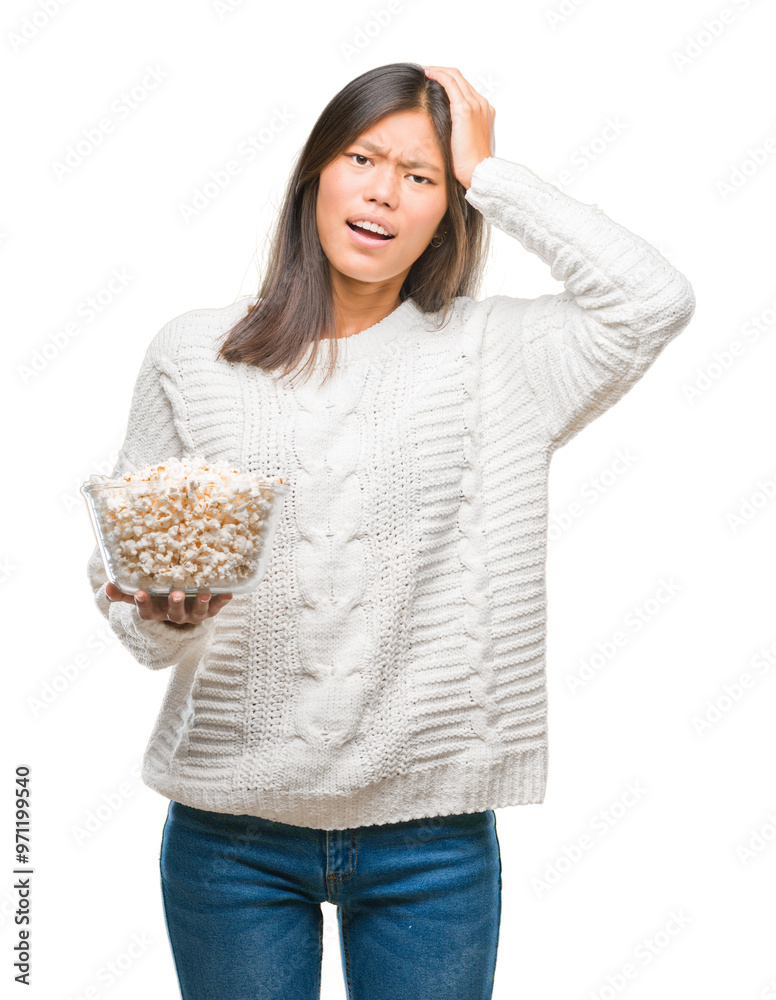 Young asian woman eating popcorn over isolated background stressed with hand on head, shocked with shame and surprise face, angry and frustrated. Fear and upset for mistake. Young asian woman eating popcorn over isolated background stressed with hand on head, shocked with shame and surprise face, angry and frustrated. Fear and upset for mistake.