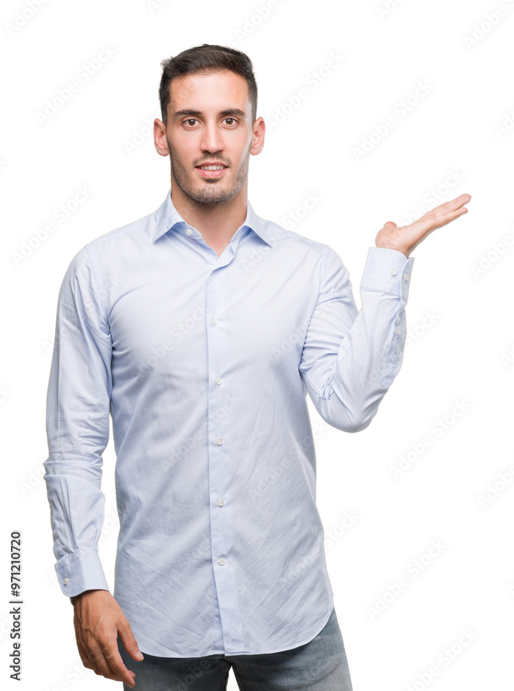 Handsome young businessman smiling cheerful presenting and pointing with palm of hand looking at the camera.