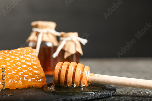 Honeycomb, dipper and honey tincture on grey textured table, closeup. Alternative medicine