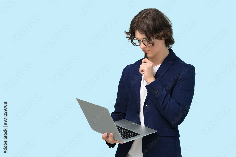 Male programmer in eyeglasses with laptop and pen on blue background Male programmer in eyeglasses with laptop and pen on blue background