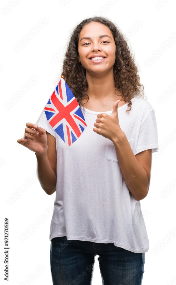 Young hispanic woman holding flag of United Kingdom happy with big smile doing ok sign, thumb up with fingers, excellent sign Young hispanic woman holding flag of United Kingdom happy with big smile doing ok sign, thumb up with fingers, excellent sign