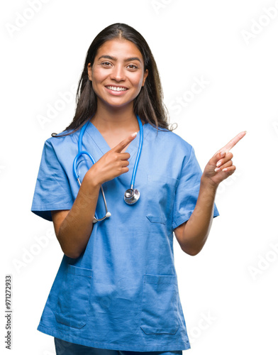 Young arab doctor surgeon woman over isolated background smiling and looking at the camera pointing with two hands and fingers to the side. photo