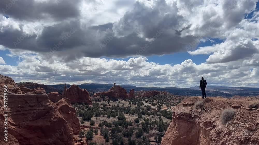 A man stands on a cliff edge in the desert, looking out at the amazing rock formations and vast landscape. The cloudscape is stunning against the blue sky. Kodachrome Basin State Park, Utah, USA A man stands on a cliff edge in the desert, looking out at the amazing rock formations and vast landscape. The cloudscape is stunning against the blue sky. Kodachrome Basin State Park, Utah, USA
