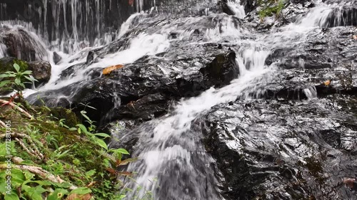 The water from the waterfall flows down the rocks, giving a refreshing feeling.