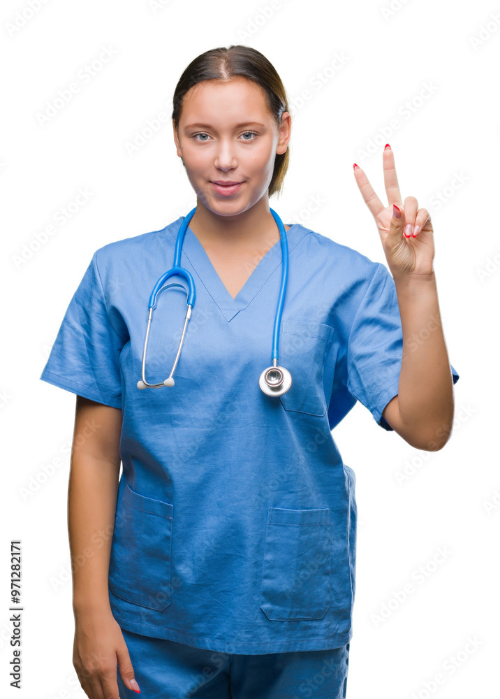 Young caucasian doctor woman wearing medical uniform over isolated background showing and pointing up with fingers number two while smiling confident and happy. Young caucasian doctor woman wearing medical uniform over isolated background showing and pointing up with fingers number two while smiling confident and happy.