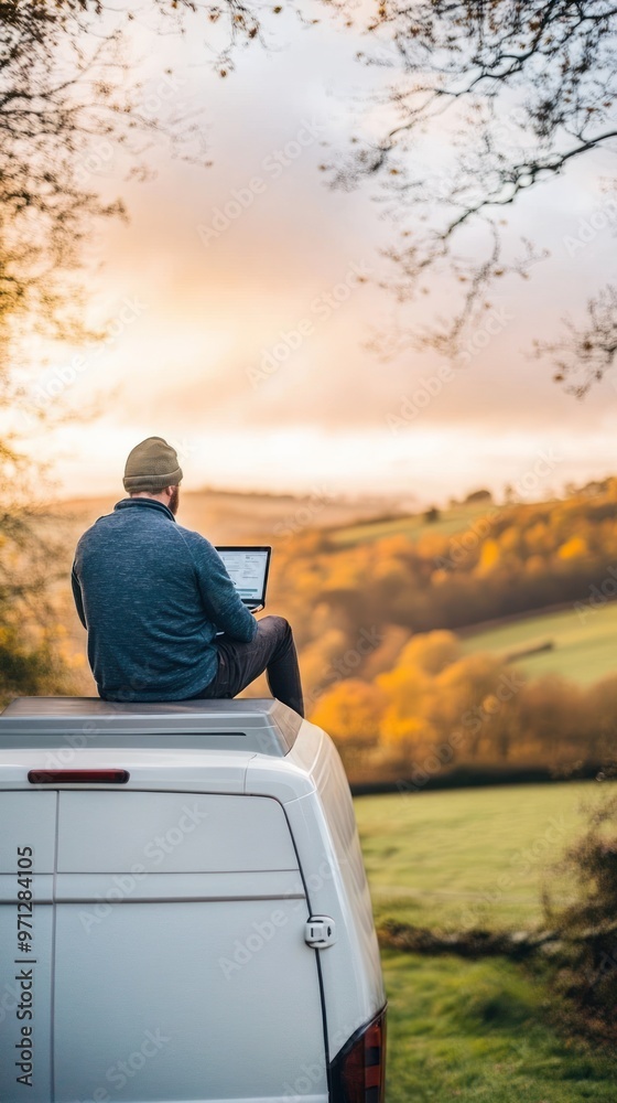 Fototapeta premium Indian man sitting atop his campervan working on a laptop, combining travel with remote work, hybrid work setup