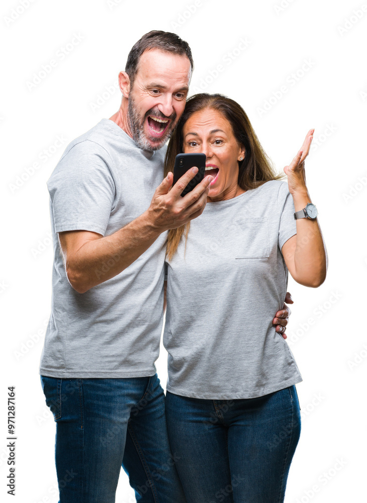 Middle age hispanic couple texting message on smartphone ver isolated background very happy and excited, winner expression celebrating victory screaming with big smile and raised hands Middle age hispanic couple texting message on smartphone ver isolated background very happy and excited, winner expression celebrating victory screaming with big smile and raised hands