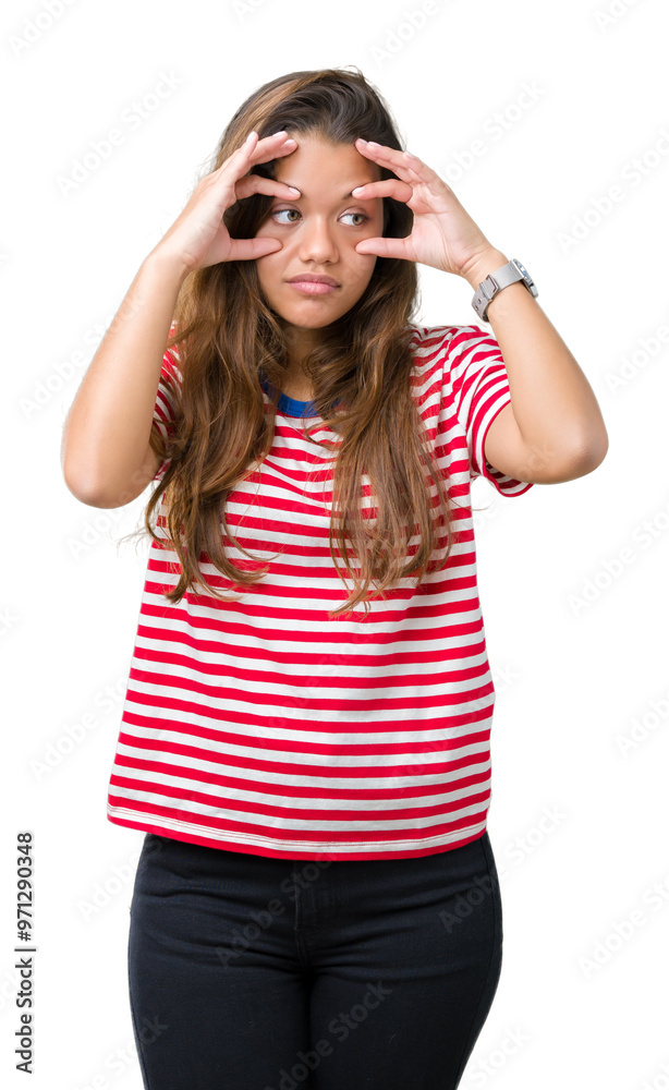 Young beautiful brunette woman wearing stripes t-shirt over isolated background Trying to open eyes with fingers, sleepy and tired for morning fatigue Young beautiful brunette woman wearing stripes t-shirt over isolated background Trying to open eyes with fingers, sleepy and tired for morning fatigue