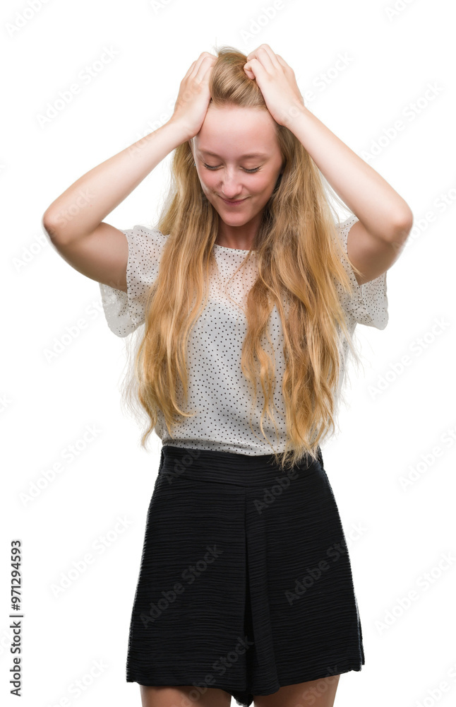 Blonde teenager woman wearing moles shirt suffering from headache desperate and stressed because pain and migraine. Hands on head. Blonde teenager woman wearing moles shirt suffering from headache desperate and stressed because pain and migraine. Hands on head.