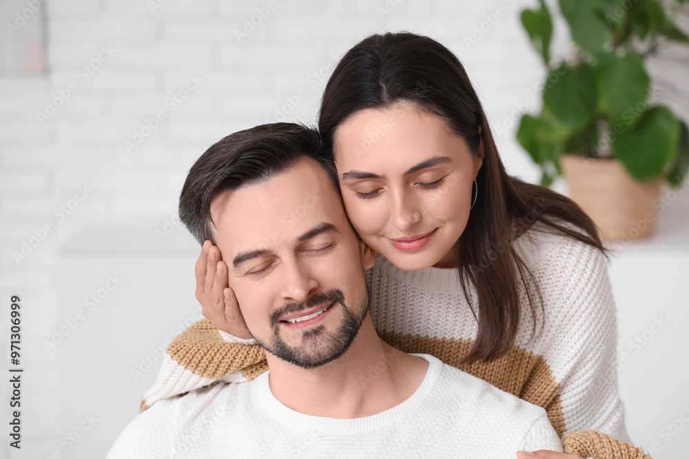 Young woman hugging her husband at home on autumn day, closeup