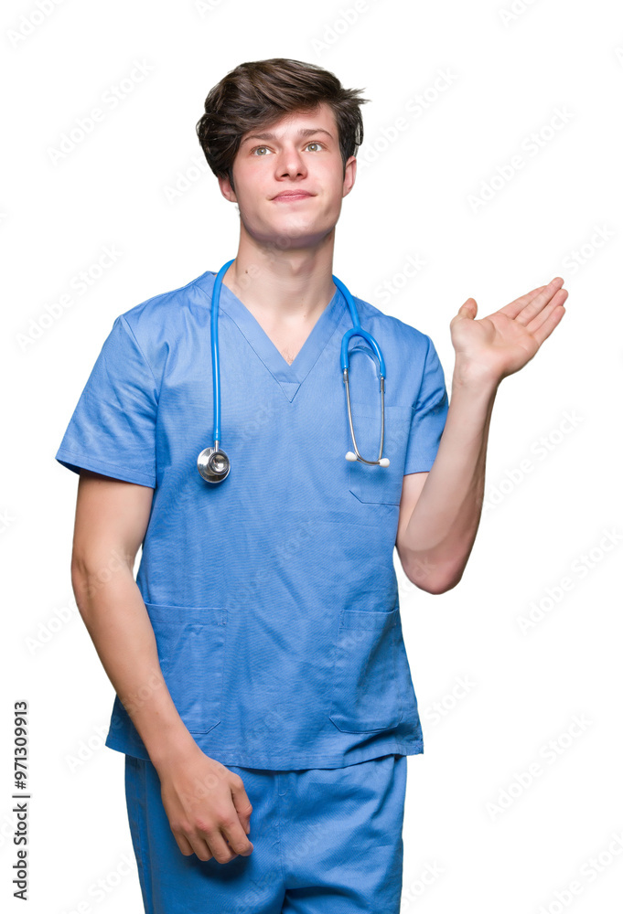 Young doctor wearing medical uniform over isolated background smiling cheerful presenting and pointing with palm of hand looking at the camera. Young doctor wearing medical uniform over isolated background smiling cheerful presenting and pointing with palm of hand looking at the camera.