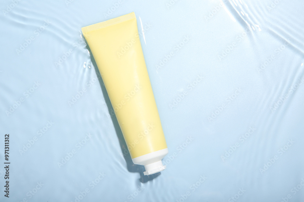 Cosmetic product. Tube with cream in water on light blue background, top view Cosmetic product. Tube with cream in water on light blue background, top view