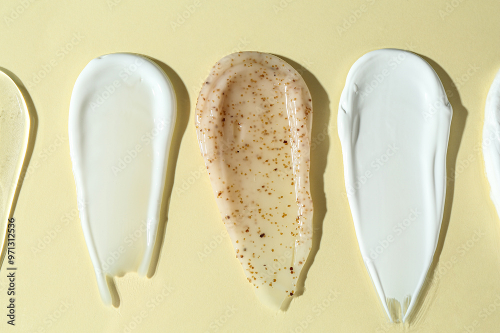 Fototapeta premium Smears of different cosmetic products on beige background, flat lay