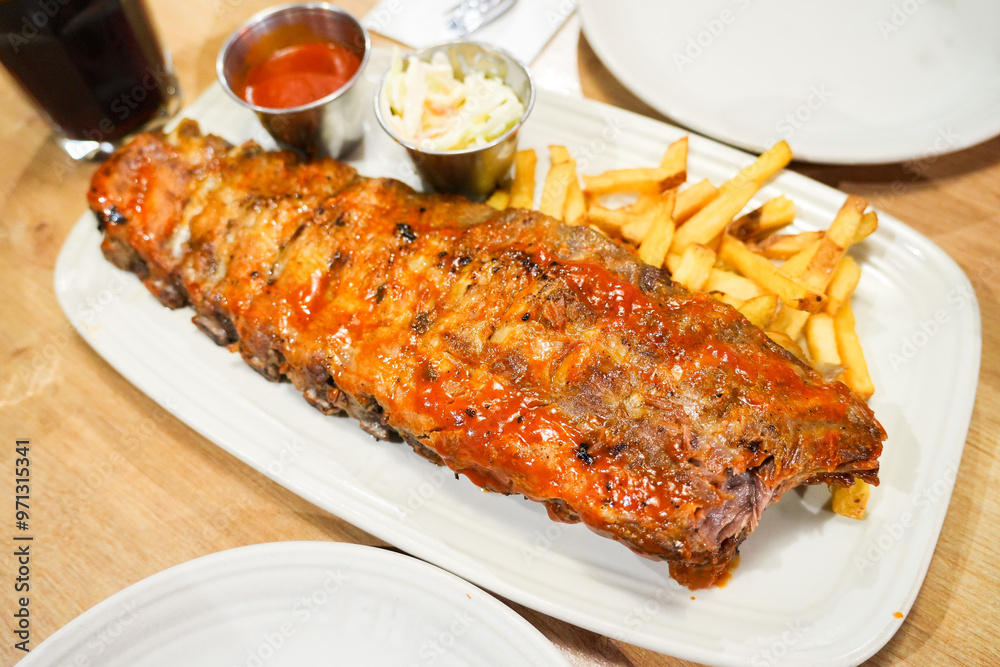 A large rack of ribs is served with a side of french fries A large rack of ribs is served with a side of french fries