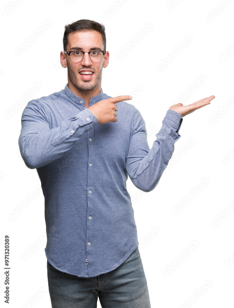 Handsome young elegant man wearing glasses amazed and smiling to the camera while presenting with hand and pointing with finger. Handsome young elegant man wearing glasses amazed and smiling to the camera while presenting with hand and pointing with finger.