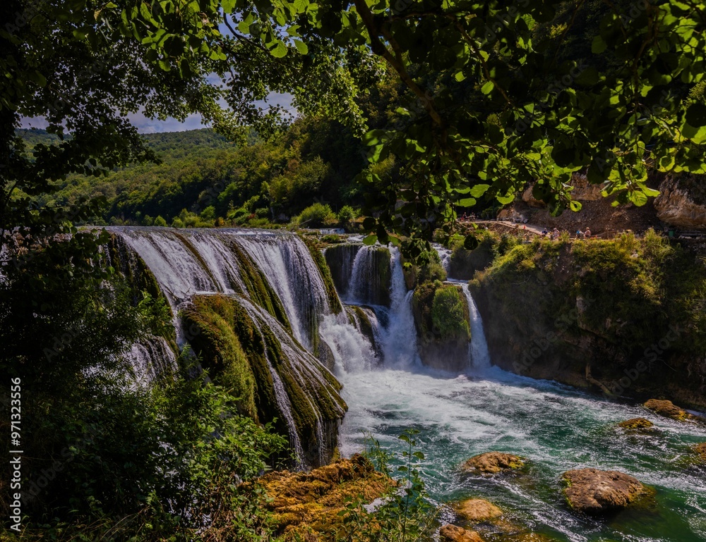 Scenic view of a waterfall surrounded by lush greenery. Scenic view of a waterfall surrounded by lush greenery.