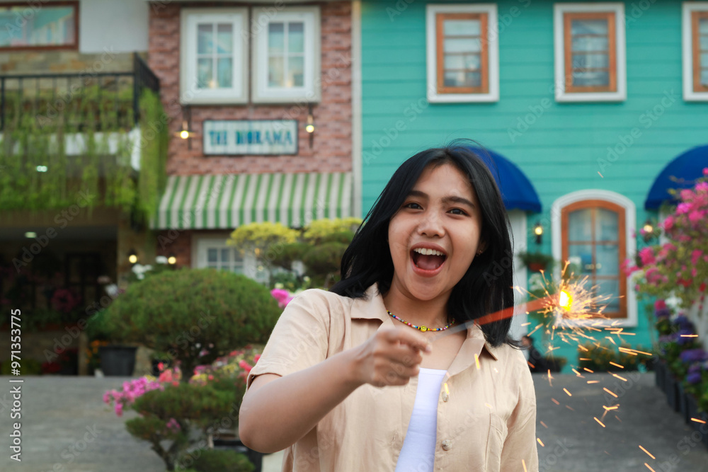 Fototapeta premium portrait of beautiful happy young asian woman holding sparklers fireworks to celebrate new year eve with garden party standing in outdoor vintage house yard