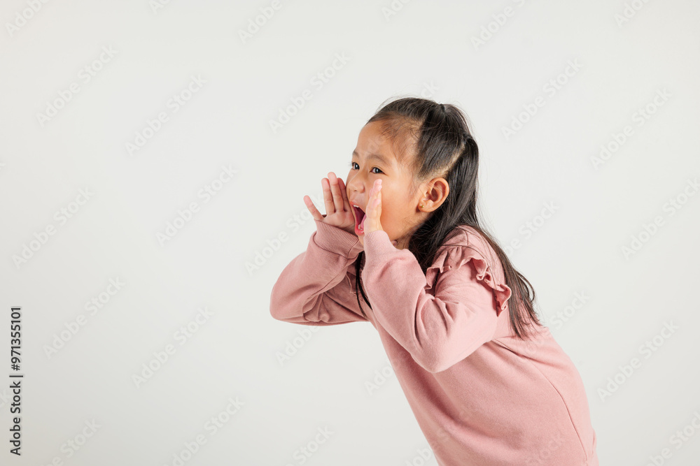 Asian happy portrait cute young kid girl standing hand on mouth talking news announcement studio shot isolated on white background, Thai kindergarten child announcement Asian happy portrait cute young kid girl standing hand on mouth talking news announcement studio shot isolated on white background, Thai kindergarten child announcement